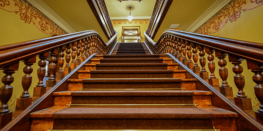 Barbers Flooring | An image displaying a stair runner flowing up a grand staircase made of wood